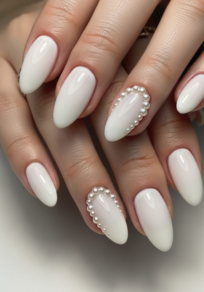 Milky white nails with small pearl studs near the cuticle on two accent fingers