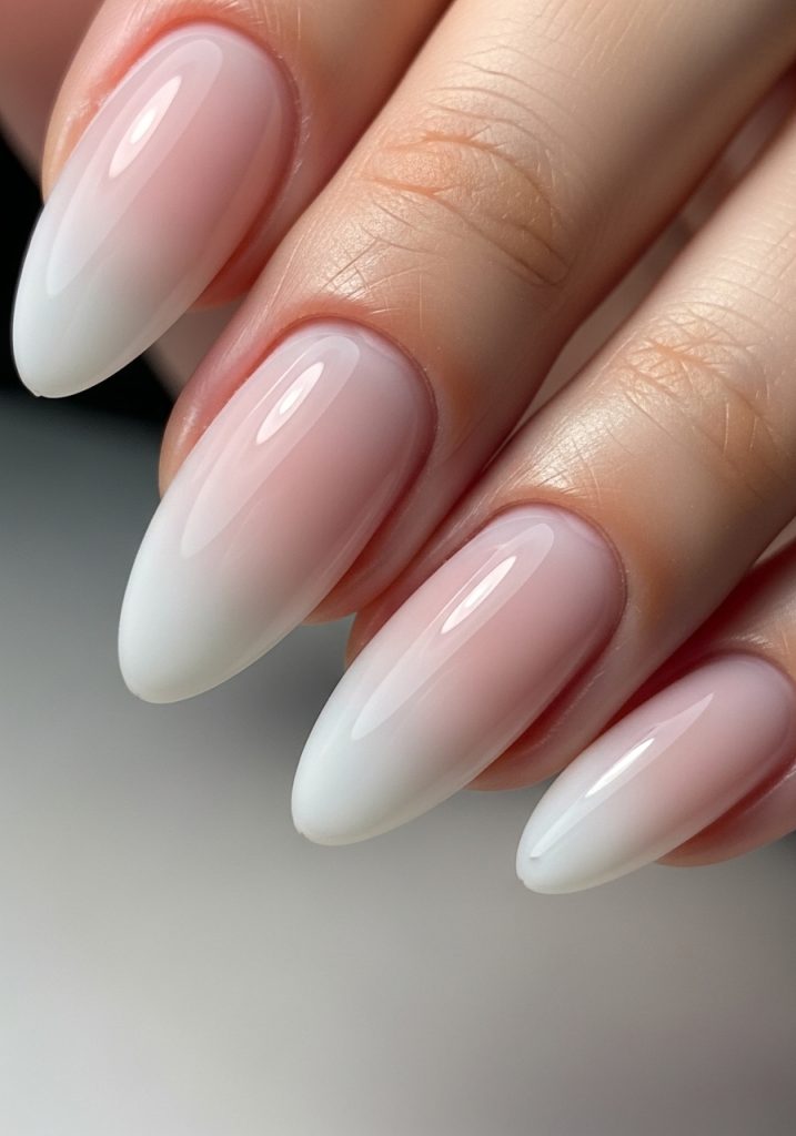 Nails with milky pink to sheer white ombre gradient, smooth transition with glossy finish