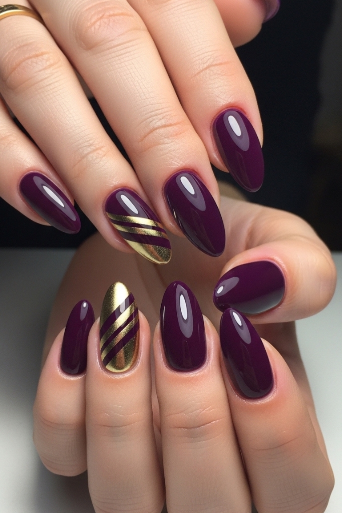 Deep purple nails with metallic gold accent stripes