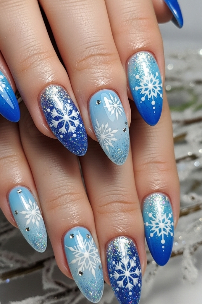 Winter-inspired nails with snowflakes and glittery blue tones, festive nail design