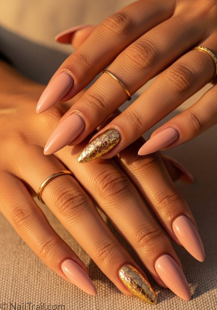 Nude pink stiletto nails with gold foil on warm medium skin hands